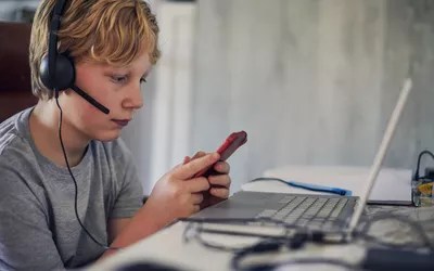 Boy listening to music and using his mobile phone and laptop