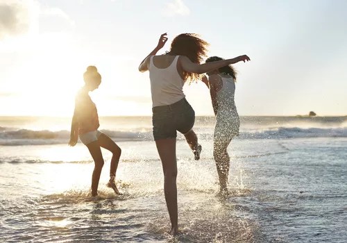 Young women hanging out at the beach, at sunset