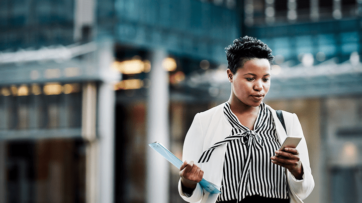 Woman in business apparel checking a phone in a downtown setting