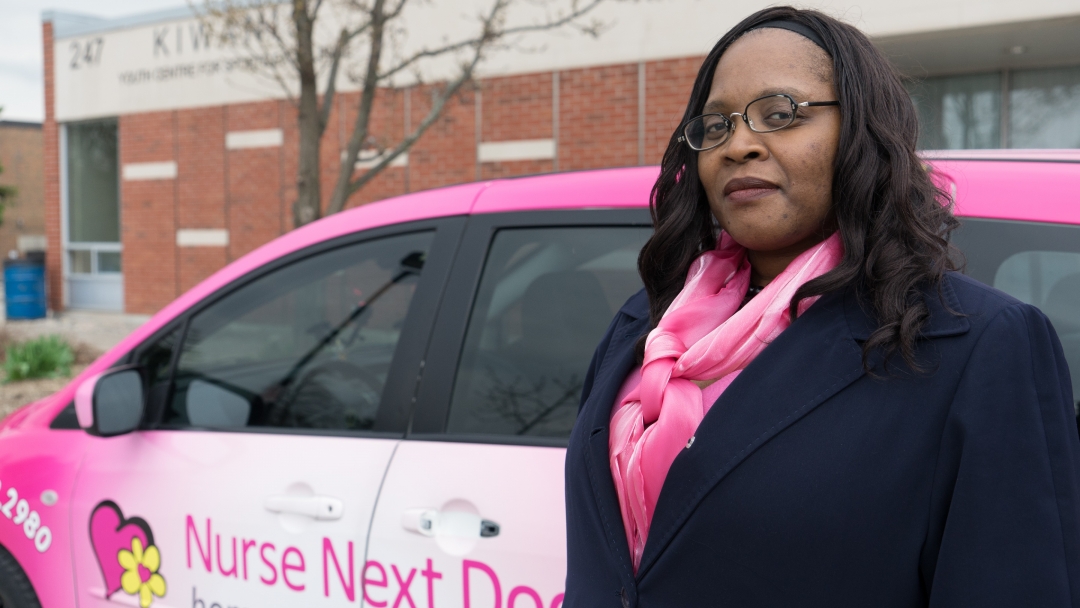 Nathalea stands in front of a Nurse Next Door company vehicle