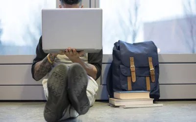 College student using laptop on floor
