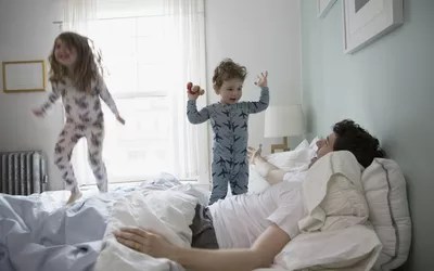 dad with kids jumping on bed